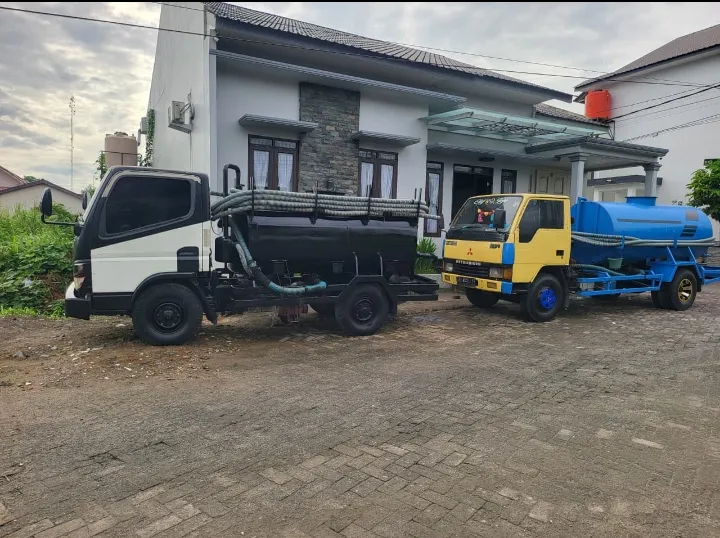 Dua truk tangki sedot terparkir di depan rumah