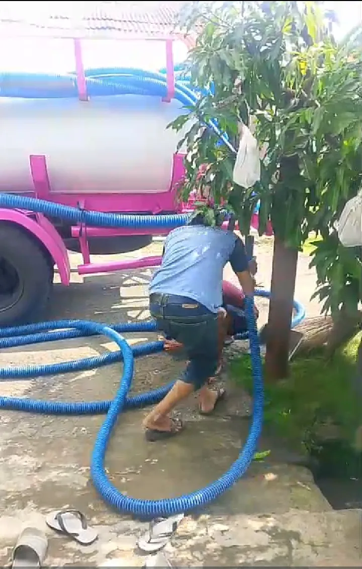 Petugas menarik selang biru dari truk tangki