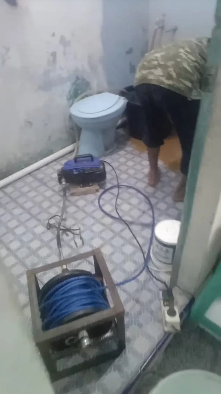 Petugas membersihkan saluran kamar mandi, gulungan selang di lantai